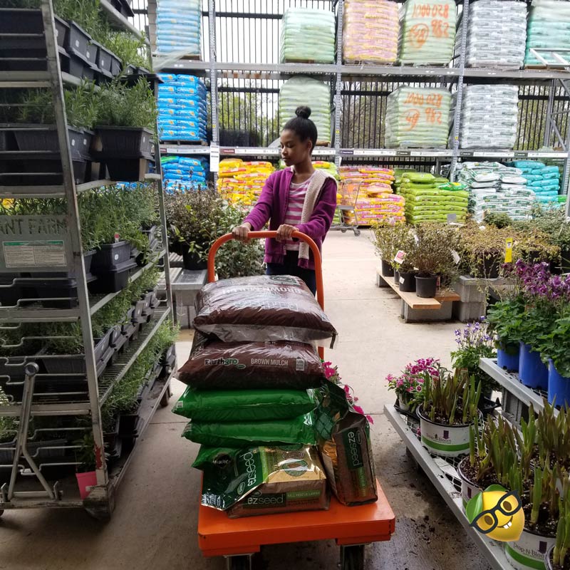 girl with a cart shopping for plants at gardening supply