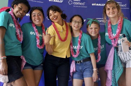 six girls smile for a photo in front of a comed ev rally backdrop