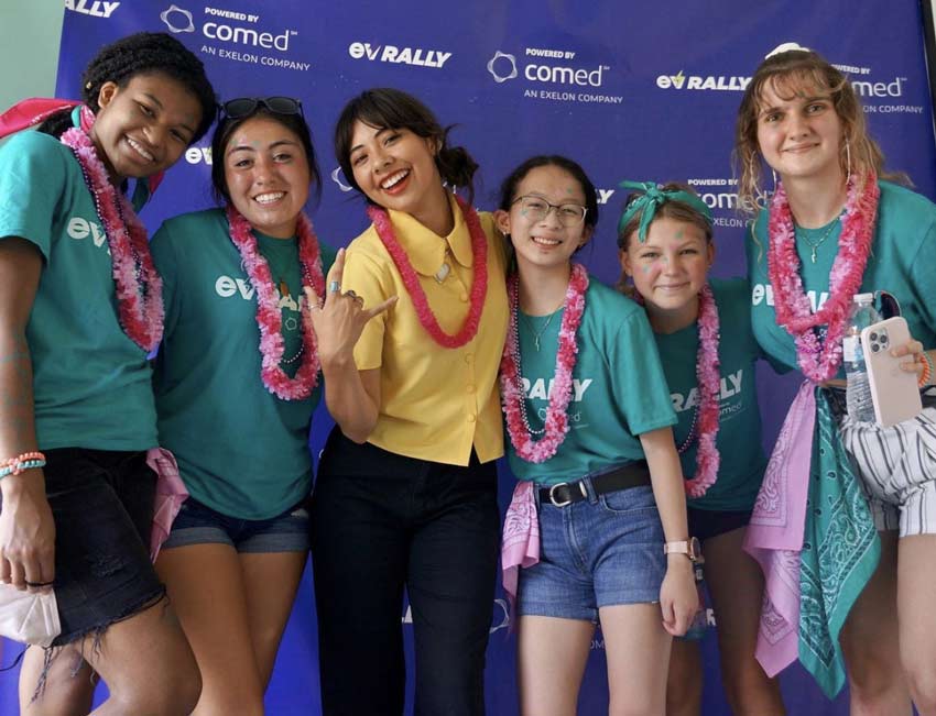 six girls smile for a photo in front of a comed ev rally backdrop